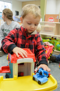 a three-year-old plays with toy trucks at the children's learning and care center
