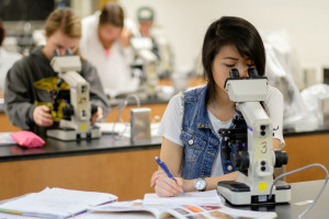 female student looks in a microscope in a biology lab on the UW Oshkosh campus